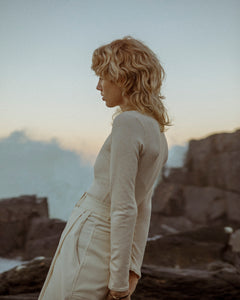 sideview of a blonde female fashion model, wearing a  luxurious cream outfit 