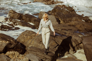 Model wearing meg taljaard trousers and jumper while walking over rocks 