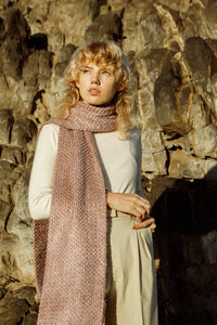 Blonde model wearing a Meg Taljaard pink scarf accessory against a rocky background 